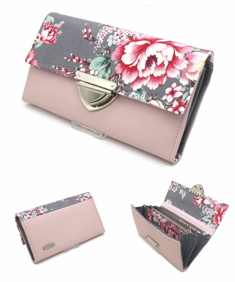 Op de afbeelding: Een roze portemonnee met een bloemenpatroon op de flap. De portemonnee heeft een zilveren sluiting en een grijs bloemenpatroon. De binnenkant is grijs en roze, met meerdere compartimenten voor kaarten en contant geld.