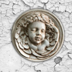 May include: A white ceramic plaque with a bas-relief sculpture of a sleeping angel with wings.