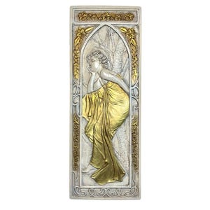 Puede incluir: Una placa de pared blanca y dorada con un diseño en relieve de una mujer con una túnica amarilla fluida. La mujer está sentada en un árbol con la cabeza apoyada en la mano. La placa está rodeada por un borde decorativo de hojas y flores.
