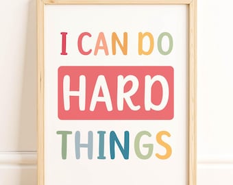 May include: Wooden framed print with the words "I CAN DO HARD THINGS" in colorful, playful lettering. The words are arranged on a white background, with a light wood frame. The print is displayed on a wooden floor.