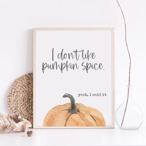 May include: A framed print featuring the text "I don't like pumpkin spice" above a watercolour pumpkin illustration. Below the pumpkin is the text "yeah, I said it". The print is in a light wood frame.