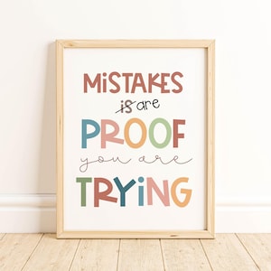 Op de afbeelding: Een ingelijste print met de woorden "Mistakes are Proof you are TRYING" in kleurrijke letters. De lijst is van licht hout en de achtergrond is wit. De print wordt weergegeven op een houten vloer.