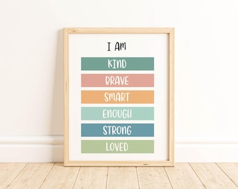 May include: A framed print with the words "I AM" at the top, followed by the words "KIND, BRAVE, SMART, ENOUGH, STRONG, LOVED" in colorful horizontal bars. The frame is light wood, and the background is white.