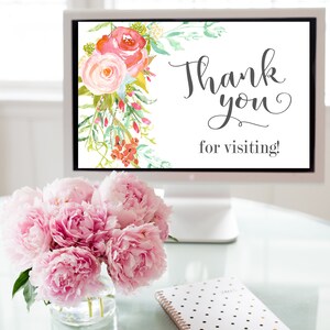 以下が含まれることがあります： モニターには、"Thank you for visiting!"の文字と水彩画の花柄が表示されています。ガラスの花瓶に入ったピンクの牡丹のブーケと、水玉模様のノートが前景にあります。