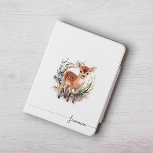 May include: White personalized cover for an e-reader with a watercolor illustration of a fawn in a wreath of flowers. The name "Jeannine" is written in cursive at the bottom.