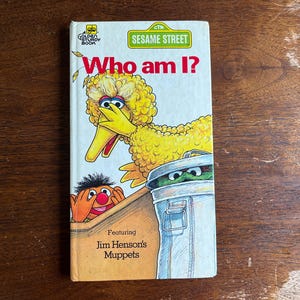 Puede incluir: Una taza de cerámica blanca con un asa negra y el texto "But First, Coffee" en negro y negrita. La taza está sobre una superficie blanca. La taza mide aproximadamente 10 cm de alto.