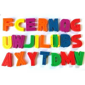 Puede incluir: Letras magnéticas del alfabeto de colores brillantes, incluyendo naranja, amarillo, morado y verde. Las letras están dispuestas en filas y están diseñadas para fines educativos o decorativos. Las letras son de un material duradero.