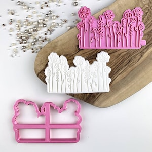 May include: Three pink silicone molds for baking and decorating cakes. The molds feature different designs of flowers and leaves.