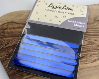 以下が含まれることがあります： 「Cakesicle Sticks」というラベルが貼られた青いケーキポップスティックの入ったパッケージ。パッケージの前面には「Lissie Lou - A Baker's Best Friend」というブランド名が印刷されています。