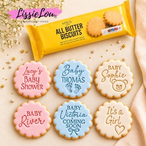 Puede incluir: Seis galletas redondas festoneadas con glaseado rosa, azul y blanco, con textos en relieve como Lucy's Baby Shower, Baby Thomas, Baby Sophie, Baby River, Baby Victoria Coming Soon e It's a Girl, junto a un paquete de M&S All Butter Biscuits.