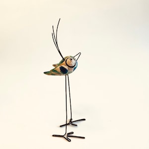 Porzellanvogel mit langen Beinen und riesigen Augen. Lustiger Vogel. Ziervogel. Bunter Vogel. Geschenk für sie. Muttertag.
