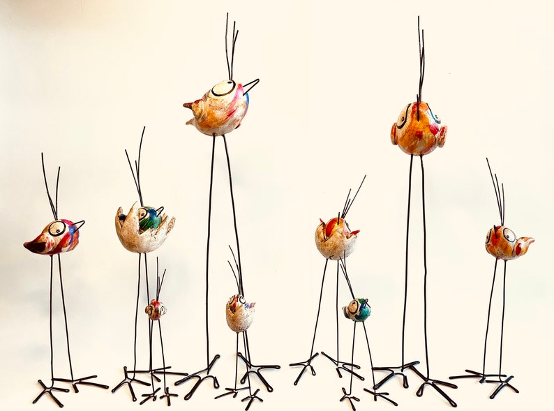 Puede incluir: Una colecci&oacute;n de nueve p&aacute;jaros de cer&aacute;mica caprichosos con detalles coloridos, posados ​​en patas de alambre delgadas y altas. Cada p&aacute;jaro tiene un dise&ntilde;o y una expresi&oacute;n &uacute;nicos, lo que agrega un toque l&uacute;dico a cualquier decoraci&oacute;n.