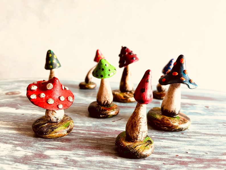 Puede incluir: Una colecci&oacute;n de setas en miniatura hechas a mano con dise&ntilde;os de lunares coloridos. Las setas est&aacute;n hechas de arcilla y pintadas en varios colores, incluyendo rojo, verde, azul y negro. Cada seta tiene un dise&ntilde;o &uacute;nico y se muestra en una peque&ntilde;a base.