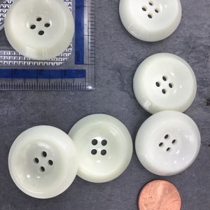 May include: Five white plastic buttons with four holes each. The buttons are approximately 1 inch in diameter.