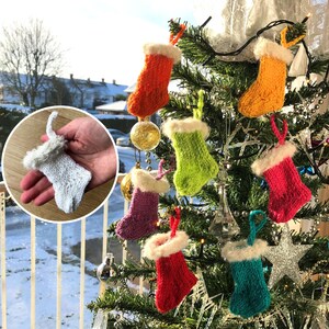 May include: A collection of miniature knitted Christmas stockings in vibrant colours including orange, yellow, lime green, pink, purple, red, and teal, each featuring a white fuzzy cuff and a matching hanging loop, with one white stocking shown separately.