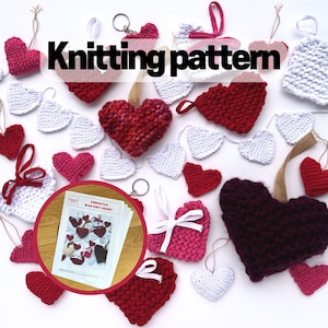 Könnte beinhalten: Eine Sammlung gestrickter Herzen in verschiedenen Farben, darunter Rot, Rosa, Weiß und Lila. Die Herzen sind auf einer weißen Oberfläche angeordnet und einige haben eine Schnur befestigt. Das Bild zeigt auch ein gedrucktes Strickmuster für ein "Vielseitiges Perlenstrickherz".