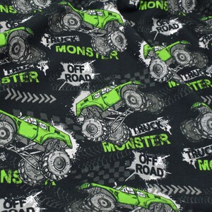 Könnte beinhalten: Schwarzer Stoff mit einem sich wiederholenden Muster aus grünen Monstertrucks mit dem Aufdruck "Truck Monster Off Road".