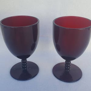 Puede incluir: Dos copas de vino de tallo rojo oscuro con un tallo con cuentas.