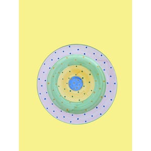 May include: A colorful, hand-painted ceramic plate with concentric circles in shades of green, yellow, and blue. The outer rim is lavender with blue polka dots. The plate is set against a yellow background.