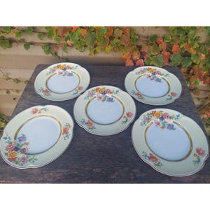 Puede incluir: Juego de cinco platos de postre vintage con estampado floral y bordes festoneados. Los platos son blancos con un borde amarillo y presentan un diseño floral colorido.