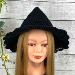 以下が含まれることがあります： 黒のクロシェ編み魔女の帽子。尖ったクラウンと幅広のつばが付いています。帽子は、長いブロンドの髪のマネキンが着用しています。
