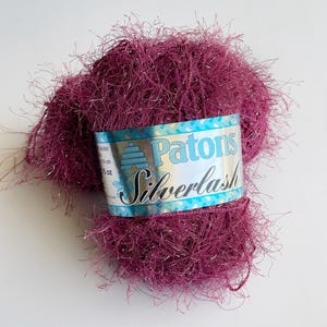 May include: A skein of Patons Silverlash yarn in a deep pink color with silver glitter threads. The label reads "Patons Silverlash".