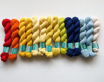 May include: A set of ten skeins of yarn in a rainbow gradient, starting with red and ending with cream. The yarn is twisted and has a soft, fuzzy texture.