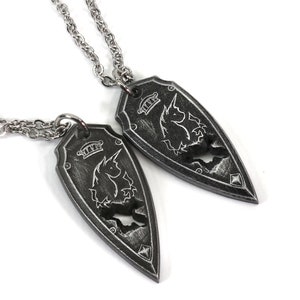 Puede incluir: Dos collares de plata con colgantes a juego. Cada colgante es un escudo de plata con un diseño de unicornio.