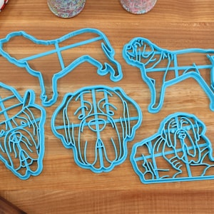 Peut inclure: Cinq emporte-pi&egrave;ces en plastique bleu en forme de chien. Les emporte-pi&egrave;ces sont sur une surface en bois. Les emporte-pi&egrave;ces sont dans diff&eacute;rentes poses, y compris un chien debout, un chien assis et une t&ecirc;te de chien.