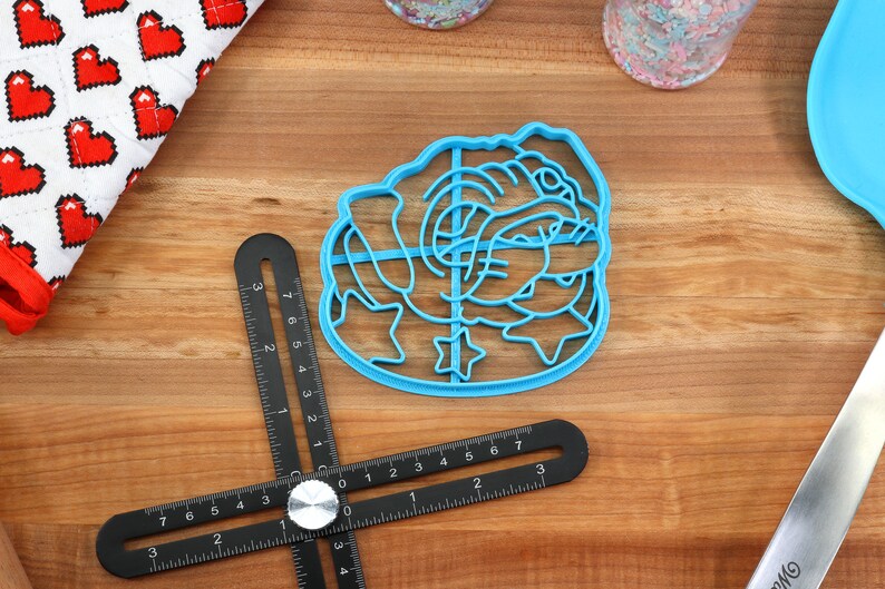 May include: A blue plastic cookie cutter shaped like a cartoon bulldog with stars around it.