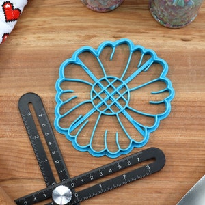 May include: A blue plastic flower-shaped cookie cutter with a grid pattern in the center.