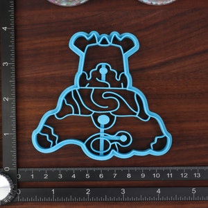 May include: A blue plastic cookie cutter shaped like a snowman with a hat and a scarf. The cutter has a detailed design with wavy lines and circles.