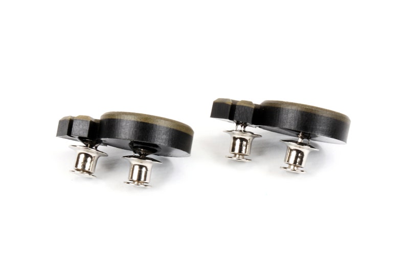 May include: Two black and green plastic buttons with silver metal posts. The buttons are shaped like a rounded rectangle with a slight curve.