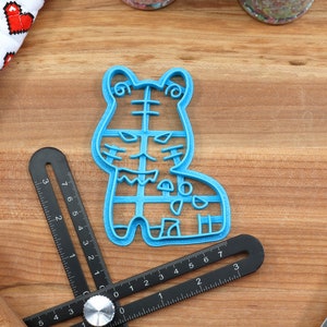 May include: Blue plastic cookie cutter shaped like a cartoon tiger. The cutter has a detailed design with stripes and spots.