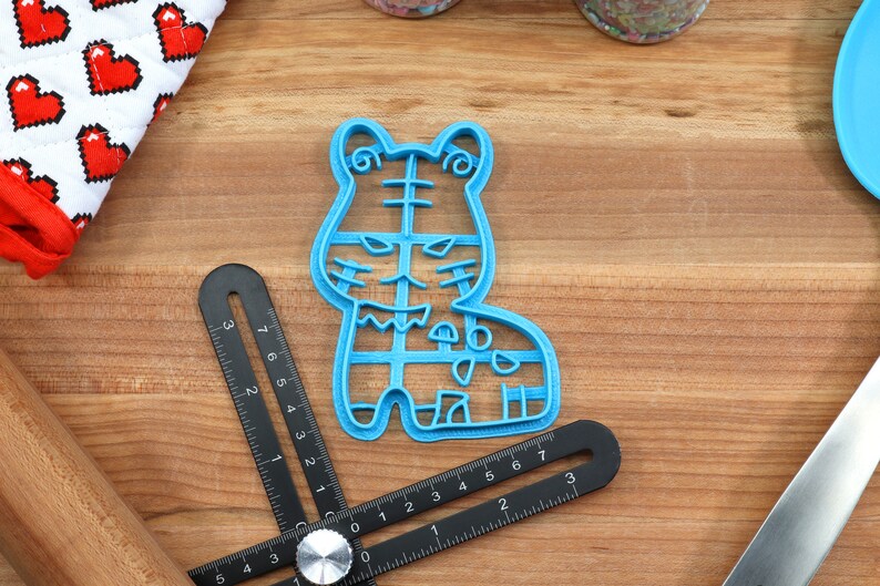 May include: Blue plastic cookie cutter shaped like a cartoon tiger. The cutter has a detailed design with stripes and spots.