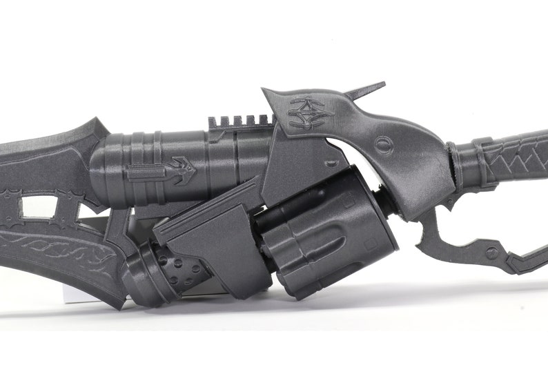 May include: A gray 3D printed sci-fi weapon with a detailed design. The weapon has a barrel, a handle, and a scope.