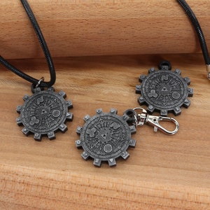 May include: Three silver-colored pendants with a detailed design, two on black cords and one on a silver chain. The pendants are shaped like gears with a circular design in the center.