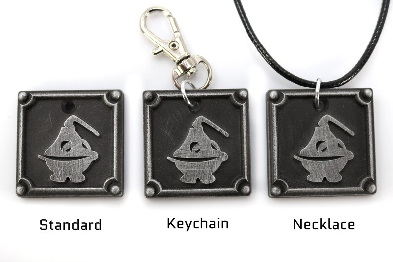 May include: Three metal pendants featuring a stylized cartoon character with a round body and a single arm. The pendants are available in three styles: standard, keychain, and necklace.