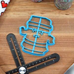 May include: Blue plastic cookie cutter shaped like a snowman with a hat and a scarf. The cutter has a detailed design with a face and buttons.