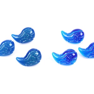 K&ouml;nnte beinhalten: F&uuml;nf blaue Glasperlen in Tropfenform mit aufwendigen Designs. Die Perlen sind in einem Halbkreis auf wei&szlig;em Hintergrund angeordnet.