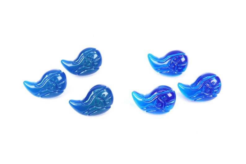 K&ouml;nnte beinhalten: F&uuml;nf blaue Glasperlen in Tropfenform mit aufwendigen Designs. Die Perlen sind in einem Halbkreis auf wei&szlig;em Hintergrund angeordnet.