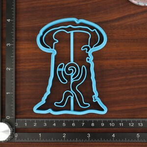 Puede incluir: Un cortador de galletas de pl&aacute;stico azul claro con forma de &aacute;rbol con un dise&ntilde;o en espiral en su interior. El cortador de galletas est&aacute; sobre una superficie de madera.