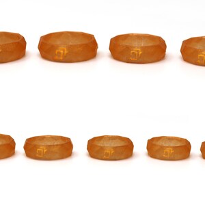 May include: Eight orange silicone rings with a geometric design and a gold inscription. The rings are arranged in two rows of four.