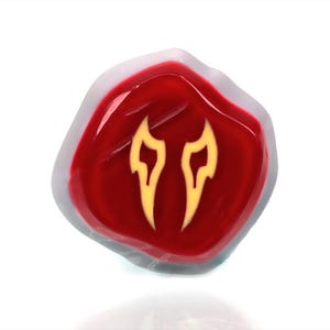 May include: A red resin dice with a white border and a yellow flame design.