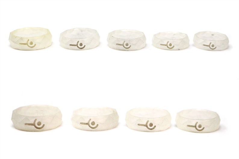 May include: Ten white silicone rings with a geometric design and a small symbol in the center. The rings are arranged in two rows of five.