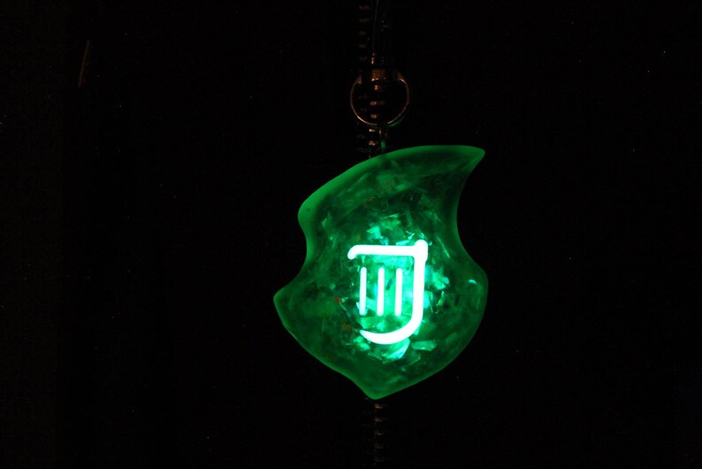 Op de afbeelding: Een groene, doorschijnende hanger met een wit harp symbool erin. De hanger is bevestigd aan een zwart koord.