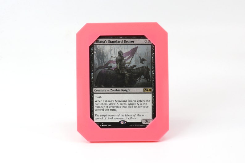 Op de afbeelding: Een zwart-witte Magic: The Gathering kaart met een roze rand. De kaart toont een zombie-ridder die een paard met een paarse vlag berijdt. De tekst op de kaart luidt "Liliana's Standard Bearer" en "Creature - Zombie Knight".