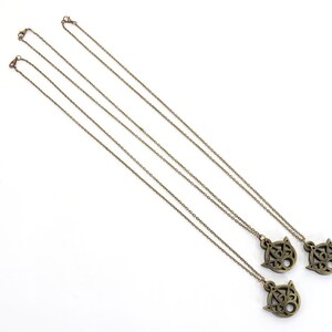 May include: Three gold necklaces with intricate pendant charms. Each charm features a detailed design with a circular shape and a pointed top.
