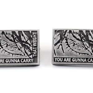 May include: Two silver pins featuring a black and white image of a tree branch and the text "You are gonna carry that weight" on each pin.