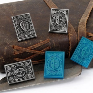 Op de afbeelding: Vier emaillepins met een gestileerd zon- en maandesign. Twee pins zijn zilver en twee zijn blauw.